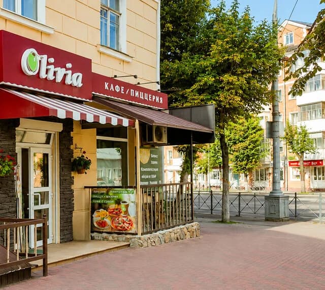 Вход в кафе Olivia на Комсомольской: бордовая вывеска и полосатая маркиза